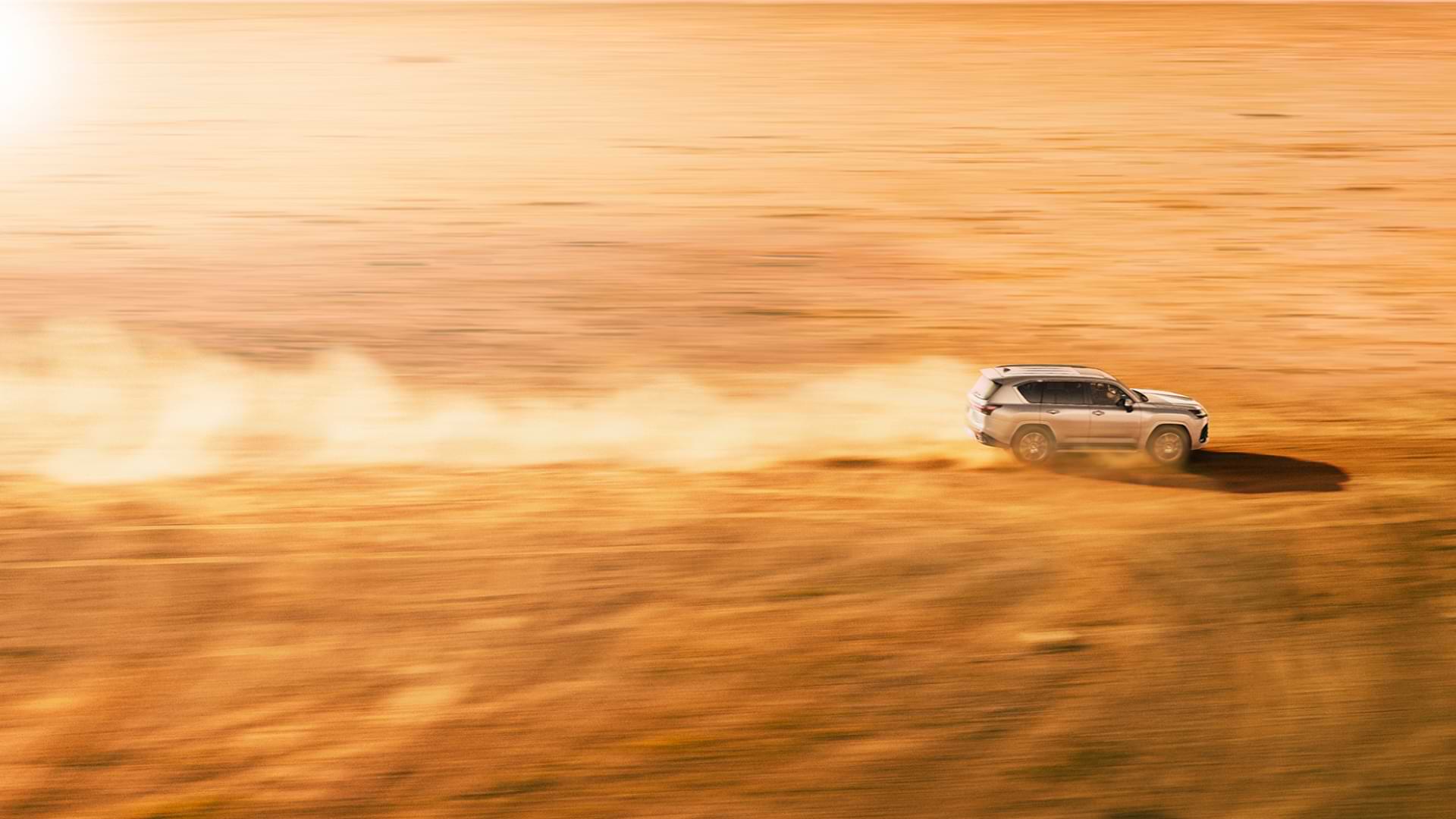 LX speeds across an orange desert, dust in it's wake.