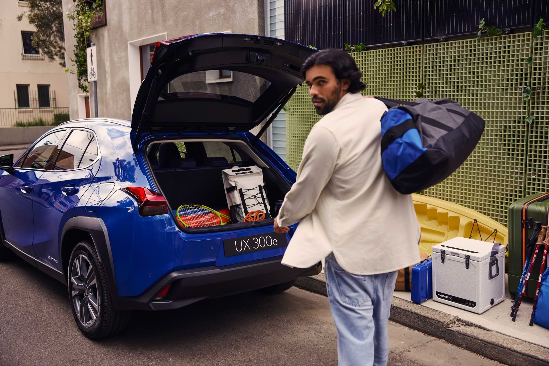 A man walks toward the full boot of a UX 300e with a bag swung over his shoulder.