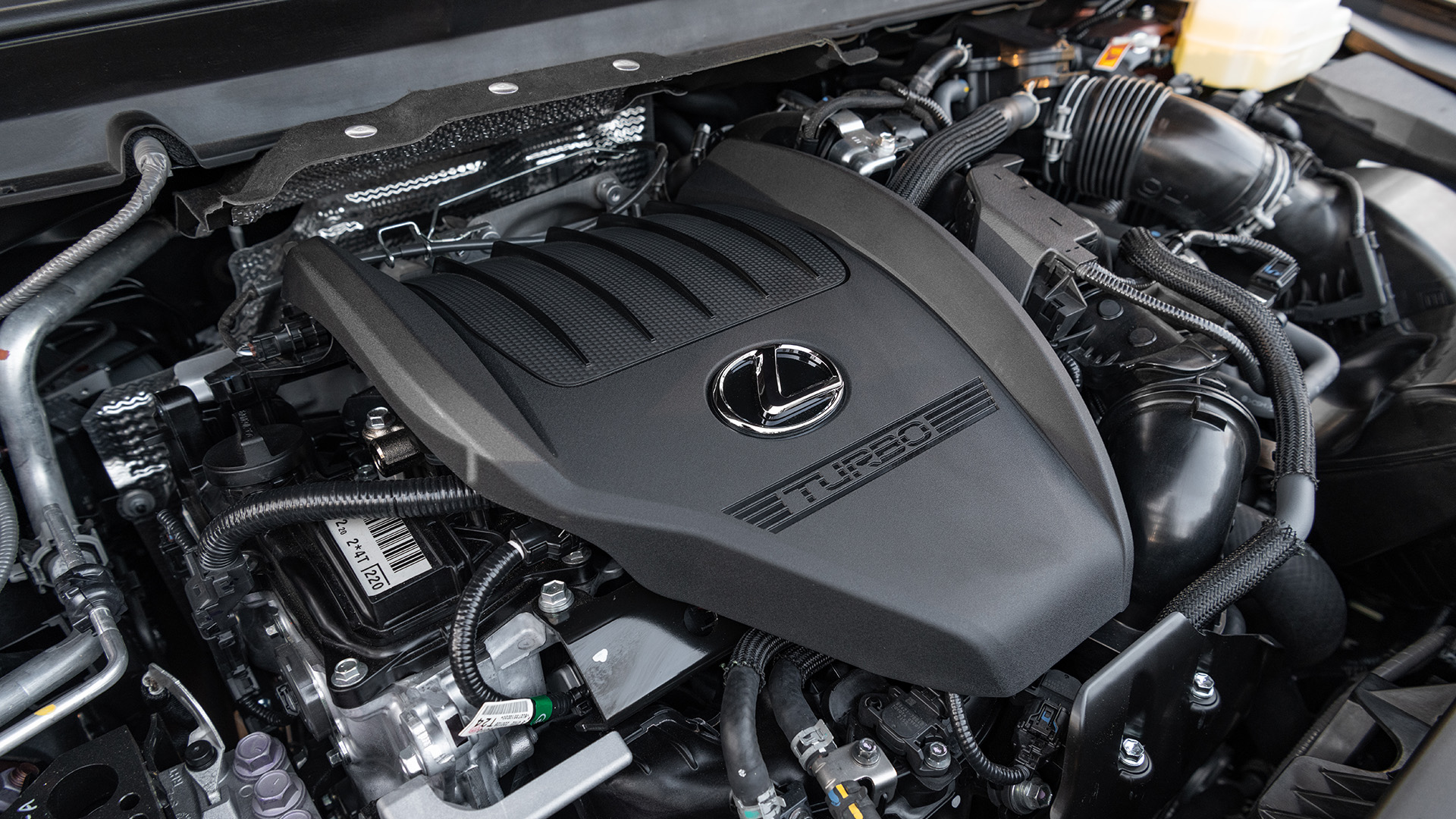 The engine bay of the RX, with the engine cover marked with the lexus logo and the word turbo. 