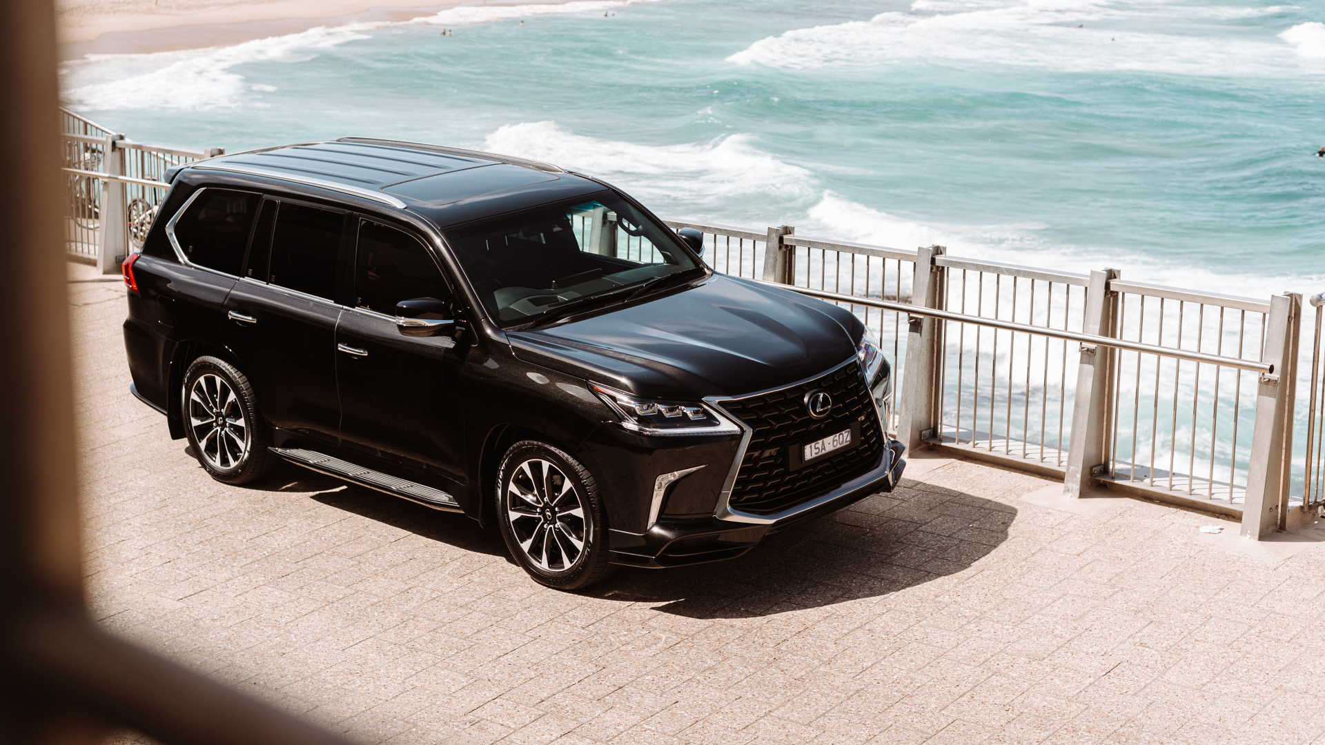 Black 2021 Lexus LX 570 S parked on pavement at a beach.
