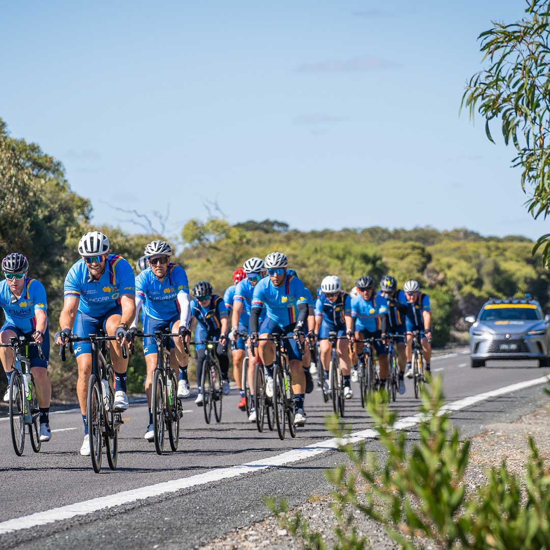 Tour de Cure cyclists riding in formation with a support vehicle following behind.