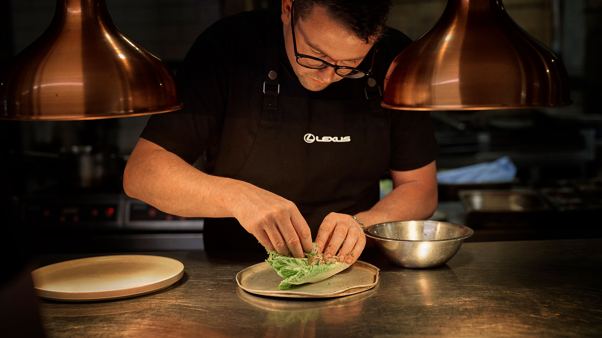 A chef prepares food under two lamps